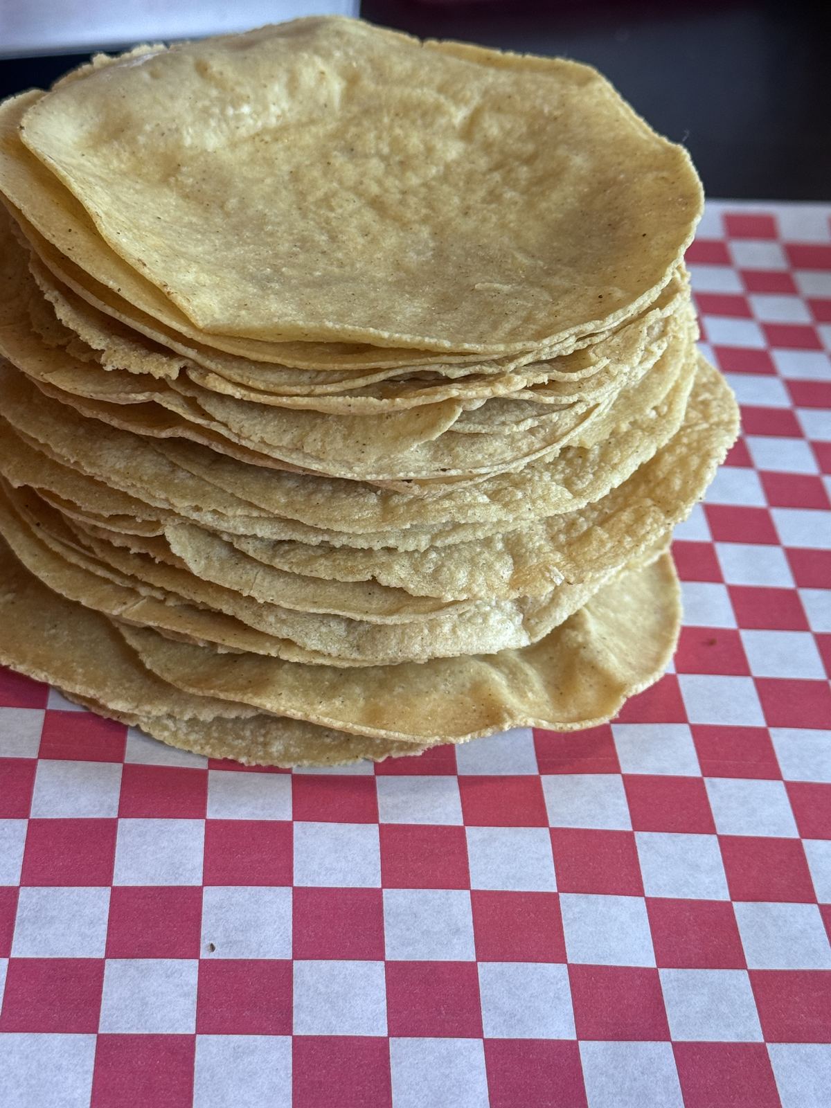 Stacks of handmade corn tortillas on red checkered paper