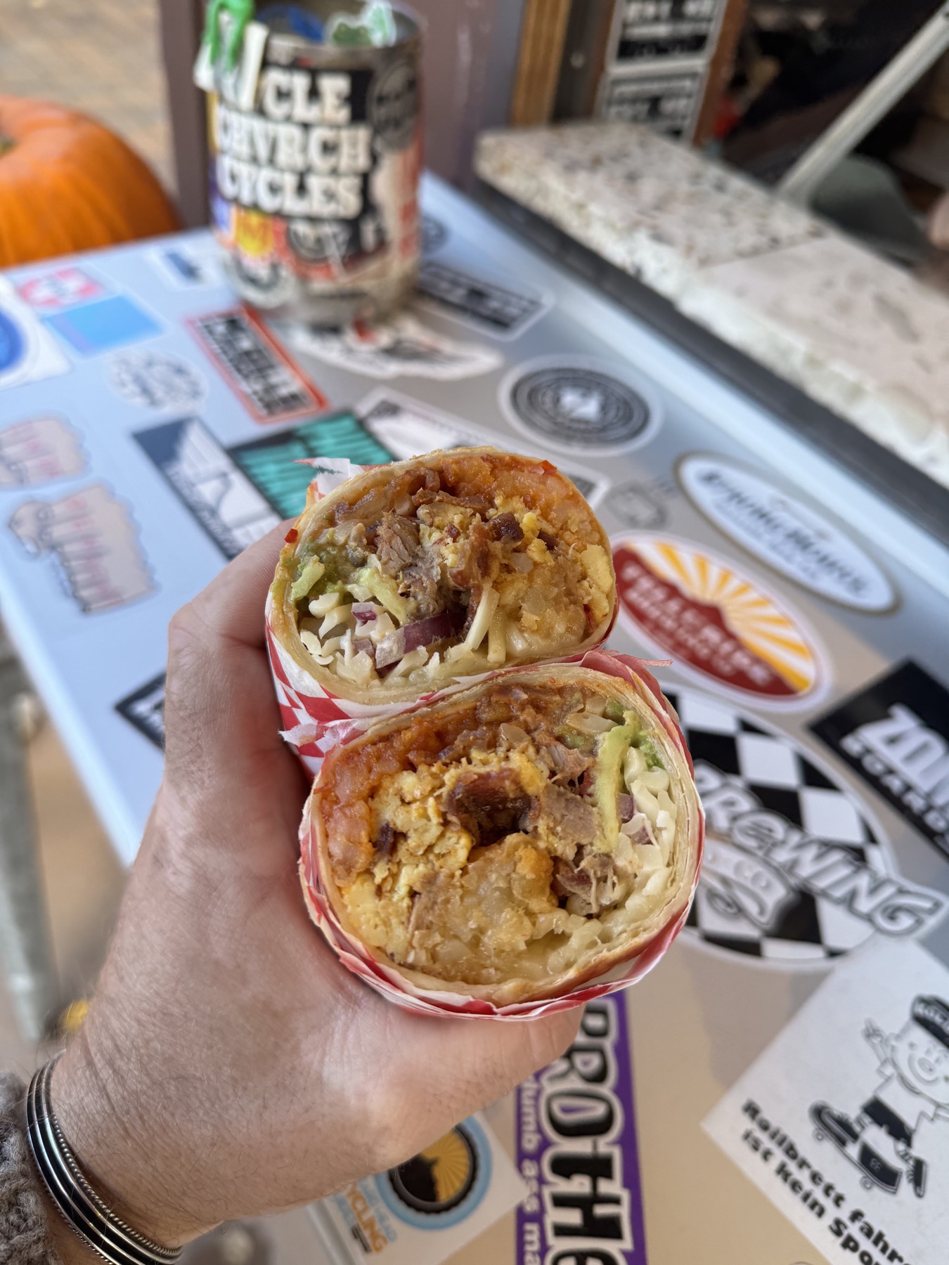 A breakfast burrito cut open to show carnitas, eggs, hash, avocado and cheese